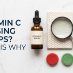 Vitamin C serum bottle with bump texture and magnifying glass caution props on white stone