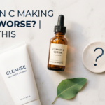 Vitamin C serum and cleanser with question mark prop on white stone in sage green tones