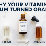 Clear and dark orange vitamin C vials with degradation arrow on white marble surface