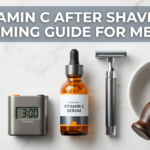 Amber vitamin C serum beside chrome razor and shaving bowl with timer prop on dark slate surface
